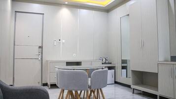 A modern kitchen with white cabinets, a dining table with four chairs, and a built-in oven.