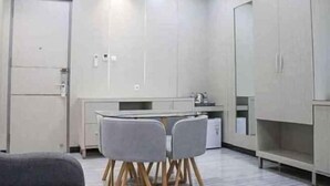 A modern kitchen with grey cabinets, a white countertop, and two grey chairs. - Helsinki Hotel Palu (South Palu)