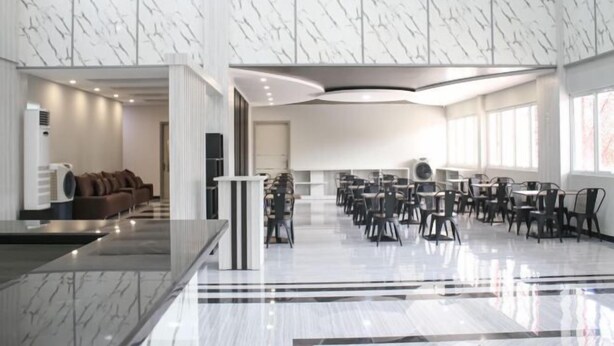 A spacious hotel lobby with a marble floor, a seating area with sofas, and a conference room with tables and chairs. - Helsinki Hotel Palu (South Palu)