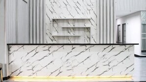 A reception desk with a marble pattern, vertical paneling, and a modern design. - Helsinki Hotel Palu (South Palu)