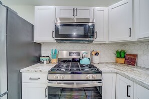 A kitchen with white cabinets, a stainless steel stove, a microwave, and a built-in oven.