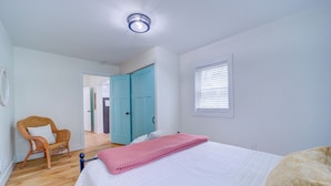 Un dormitorio con una cama, una silla, un armario y una ventana.