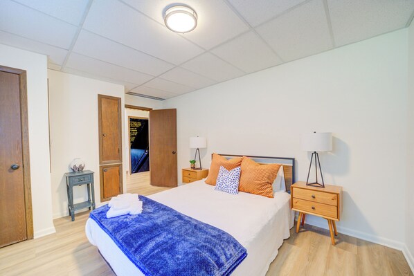 Une chambre d’hôtel comprenant un lit, deux tables de chevet, une petite table et une porte donnant sur une autre pièce.