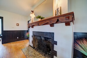 A hallway with a fireplace, wooden mantel, and a potted plant.