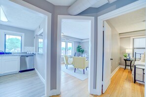 A spacious living area with a kitchen, dining area, and a bedroom with a bedside table and lamp. - Coastal Vibes - Apt E (Muskegon)