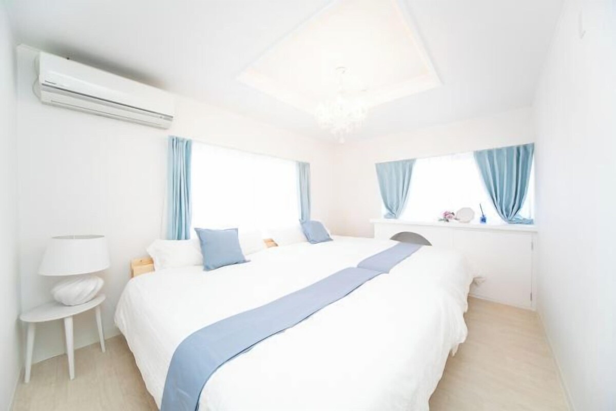 Une chambre d’hôtel avec un grand lit, une table de chevet avec une lampe et une fenêtre avec des rideaux.
