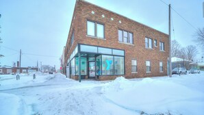 A brick building with large windows and a glass entrance. - Lovely Mid-Century Modern - Apt B (Muskegon)