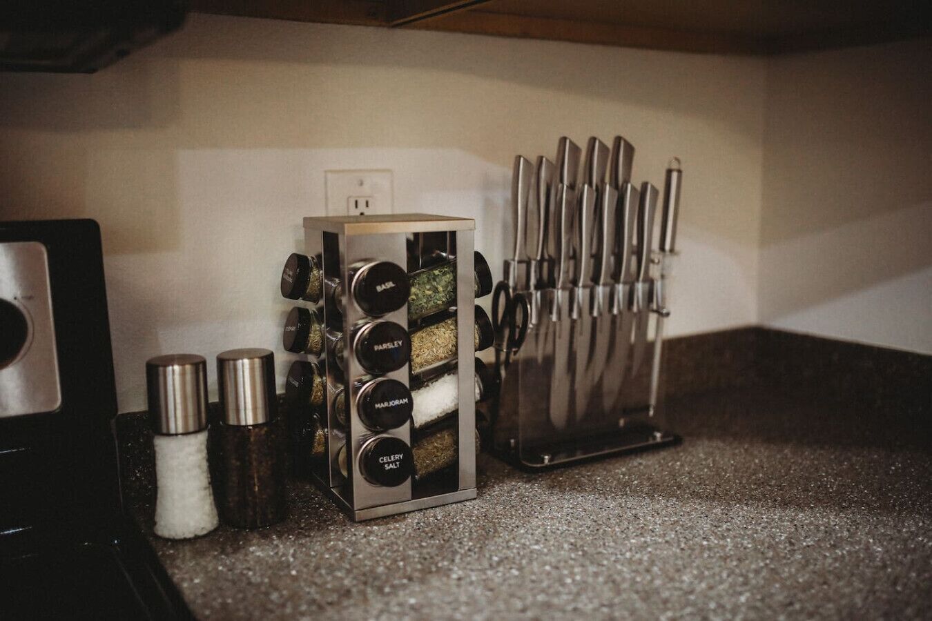 Una encimera de cocina con un especias, un juego de cuchillos y un salero.