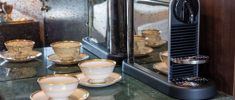 Una cafetera con varias tazas y platillos sobre una encimera.