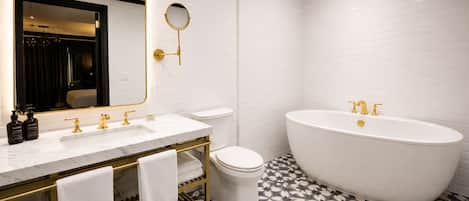 A modern bathroom with a freestanding bathtub, a vanity with gold fixtures, and a large mirror.