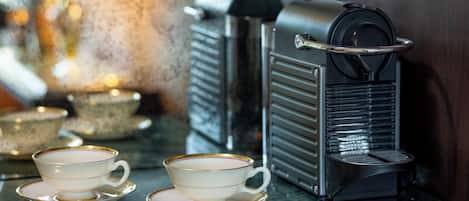 A coffee machine and two cups on a reflective surface.