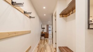 A hallway with wooden flooring, a bench, and a coat rack. - Slopeside Suite at Alyeska - Ski In Ski Out (Girdwood)
