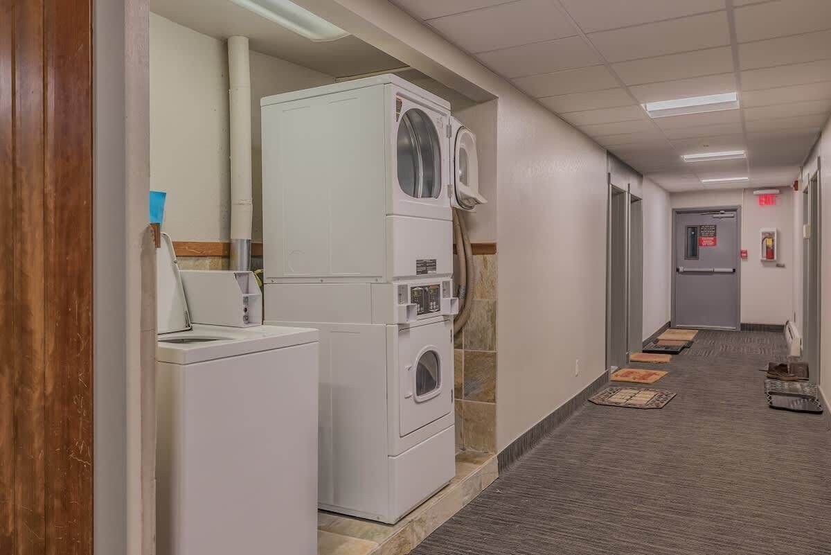 A laundry area with stacked washers and dryers, a sink, and a tiled floor.