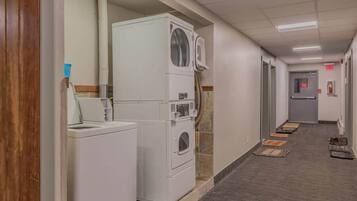 A laundry area with stacked washers and dryers, a sink, and a tiled floor.
