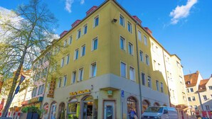 A yellow building with multiple windows and a sign that reads "Ulfia Dirum".