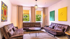A living room with two leather sofas, a round coffee table, and a window with curtains.