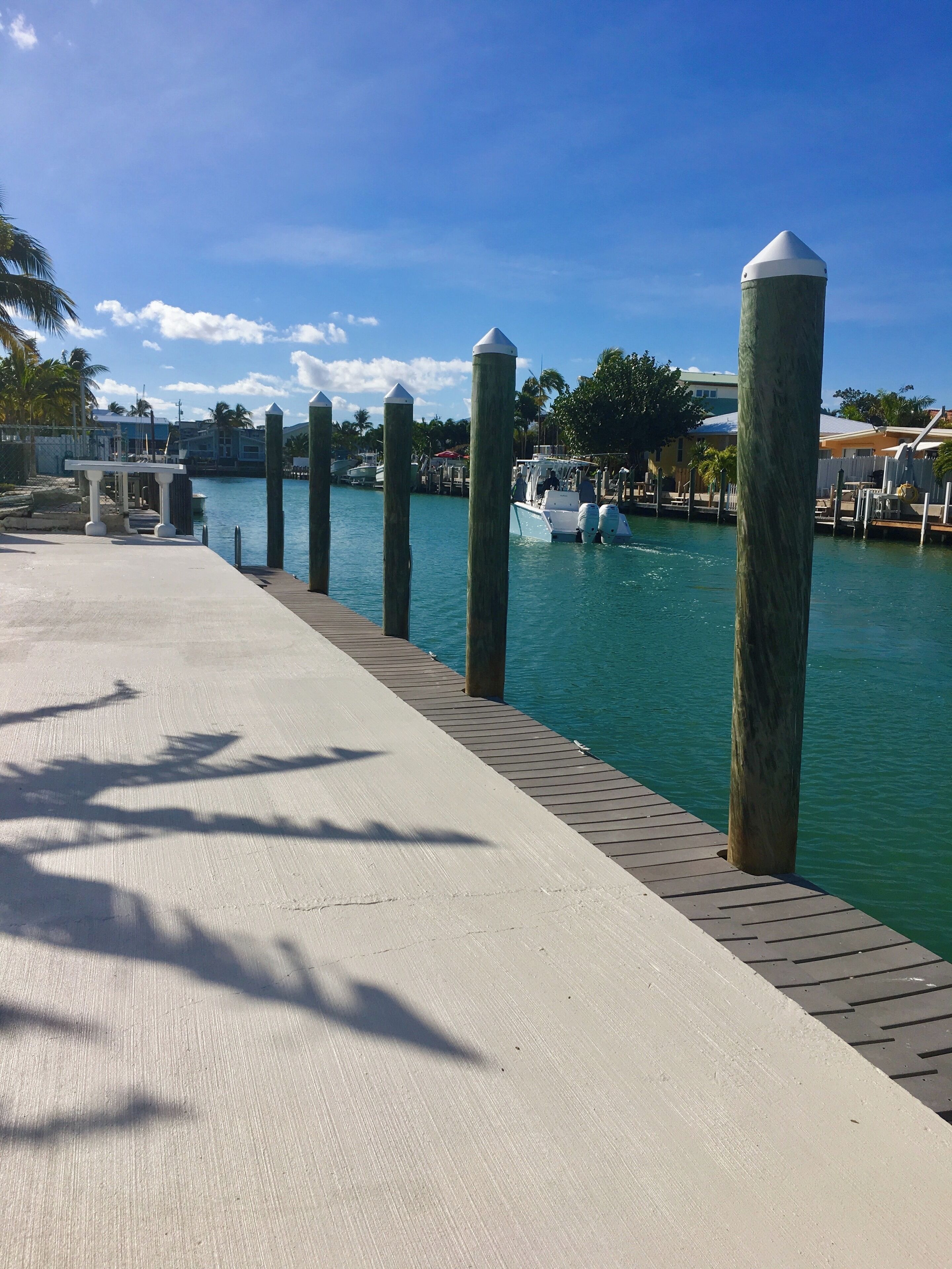 A waterfront dock with boats, a clear sky, and a wooden walkway.