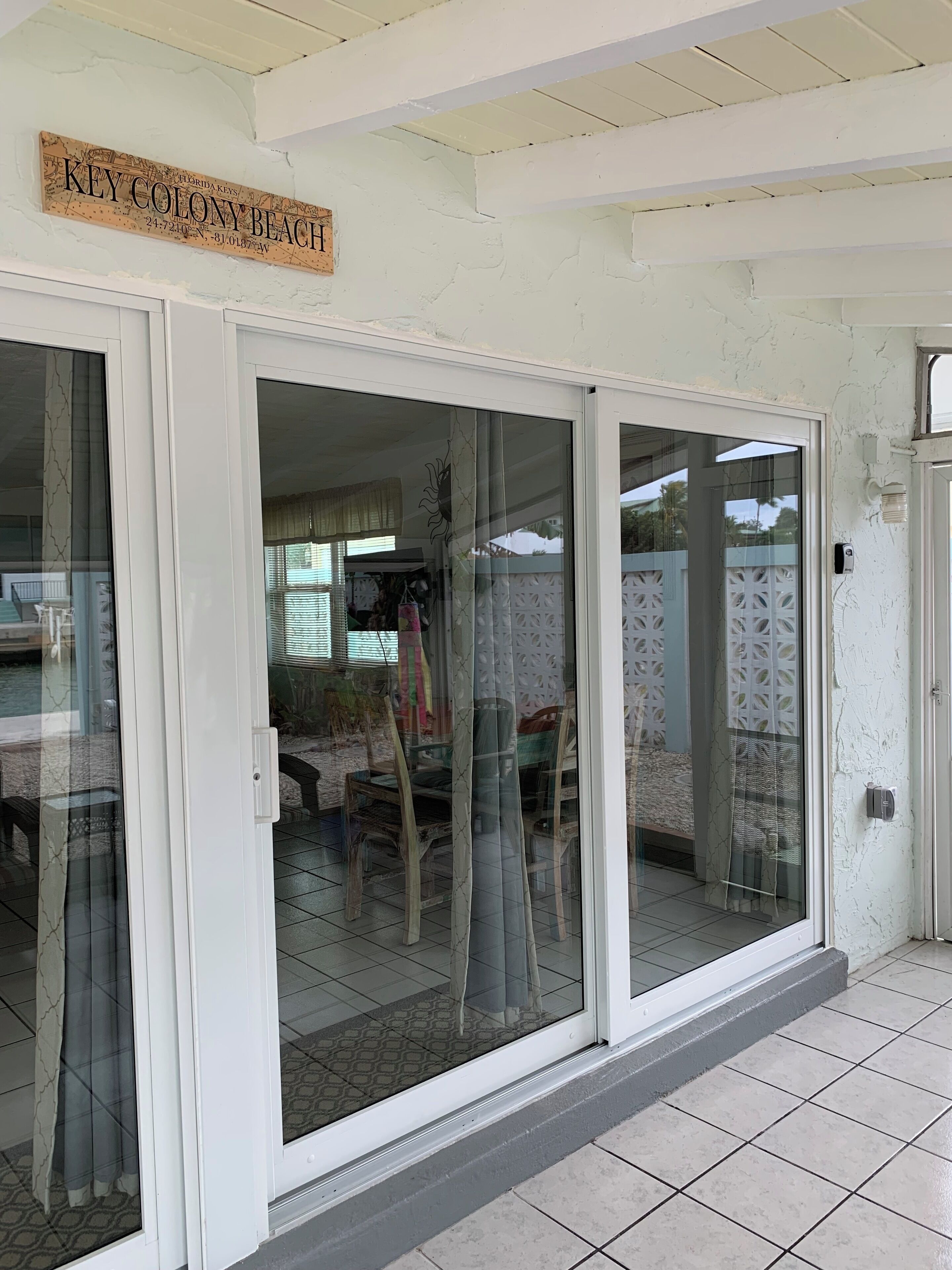 A sliding glass door leading to a patio area with a view of outdoor furniture and a decorative sign above.