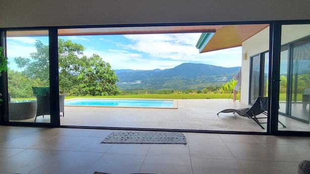 A modern interior with a large sliding glass door leading to a pool area with a mountain view. - Spacious 3 bed, 3 bath home with breathtaking Mountain and Valley views. (Platanillo)