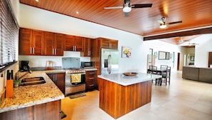 A modern kitchen with wooden cabinets, granite countertops, a stainless steel refrigerator, and a central island. - Spacious 3 bed, 3 bath home with breathtaking Mountain and Valley views. (Platanillo)