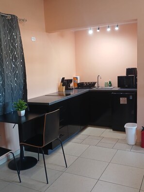 Uma cozinha compacta equipada com pia, cafeteira e micro-ondas.