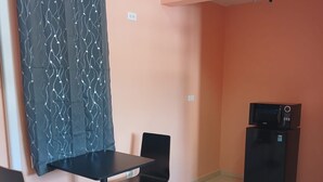 Una habitación pequeña con una mesa, dos sillas, un microondas y una cortina.