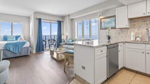 Ein modernes Interieur mit Küche, Essbereich und Schlafzimmer mit Balkon.