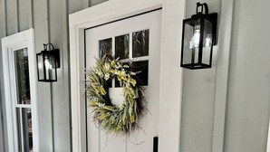 A white door with a wreath, a doormat with "hello" written on it, and a vase with yellow flowers. - Cozy Mountain Hideaway, Next to Hiking Trails & Waterfalls! (Highlands)