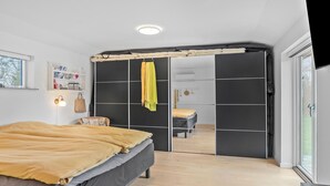 A bedroom with a bed, a wardrobe, a mirror, and a window.