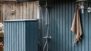 A blue wooden structure with a showerhead and a towel hanging on the wall.