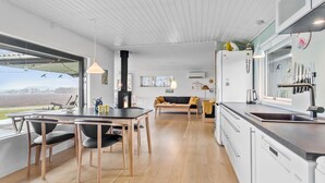 A modern kitchen with a dining area, wooden flooring, and a view of the outdoors.