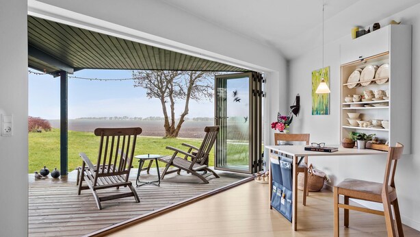 A modern kitchen with a large window, wooden deck, and a view of the outdoors.