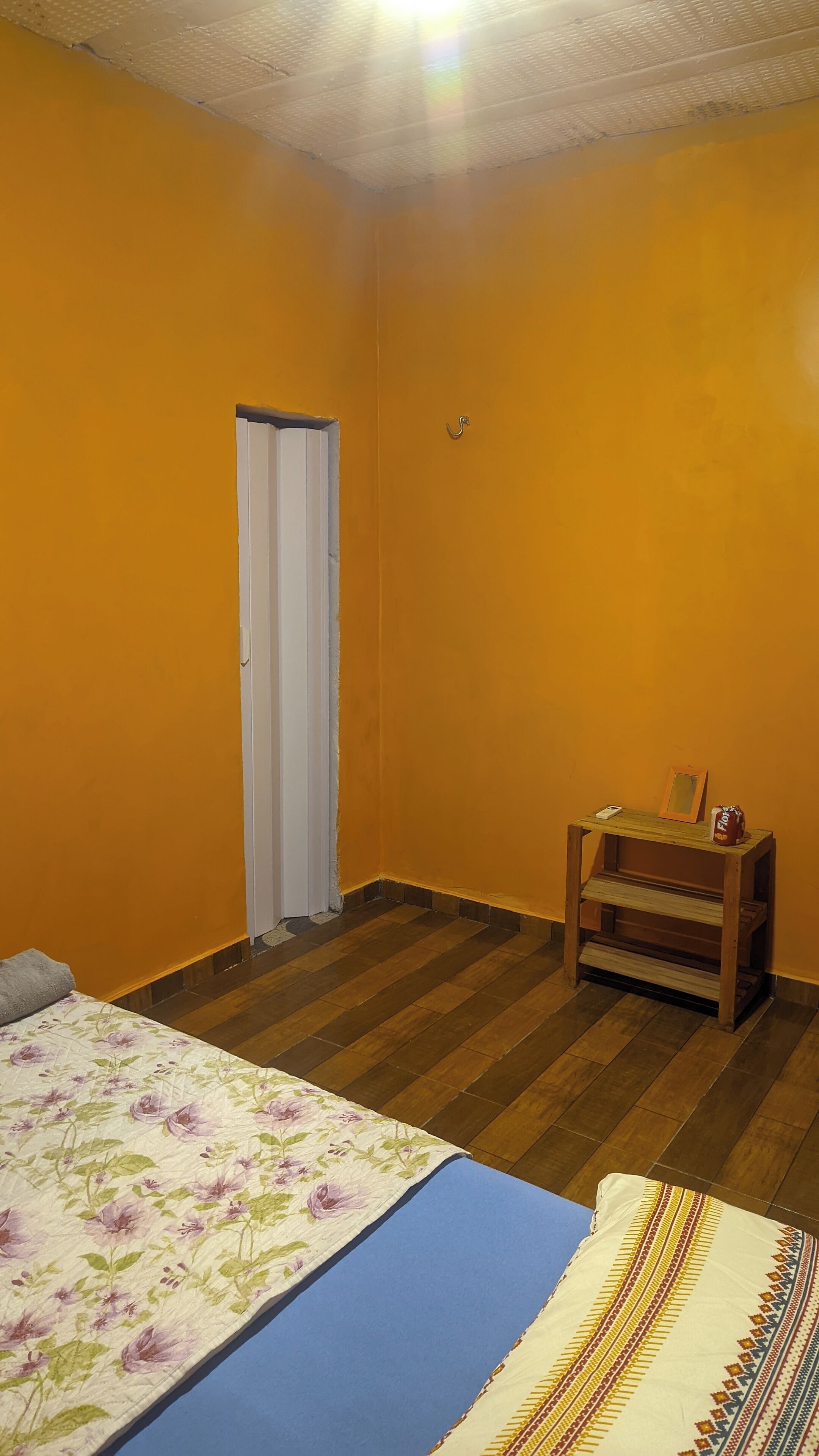 A bedroom with a bed, a small wooden table, a chair, and a door.