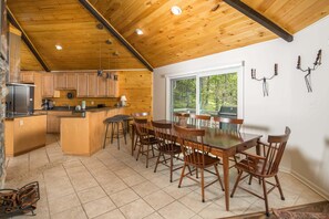 A wooden cabin interior with a kitchen, dining area, and large windows. - Charming Mountain Home with a View (Seven Devils)