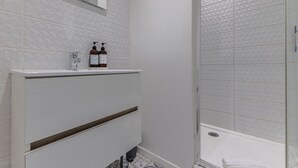 A bathroom with a white vanity, a mirror, and two bottles of shampoo. - Superb flat in beautiful Bordeaux stone for 2p (Bordeaux)