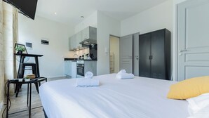 A hotel room with a bed, a desk, a kitchenette, and a wardrobe. - Superb flat in beautiful Bordeaux stone for 2p (Bordeaux)