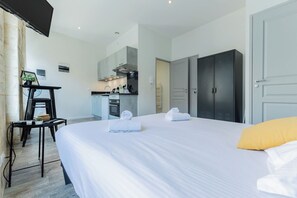 Una habitación de hotel con cama, escritorio, kitchenette y armario.