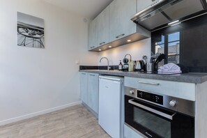 Een moderne keuken met roestvrijstalen apparatuur, een vaatwasser en een aanrecht met diverse keukengerei.