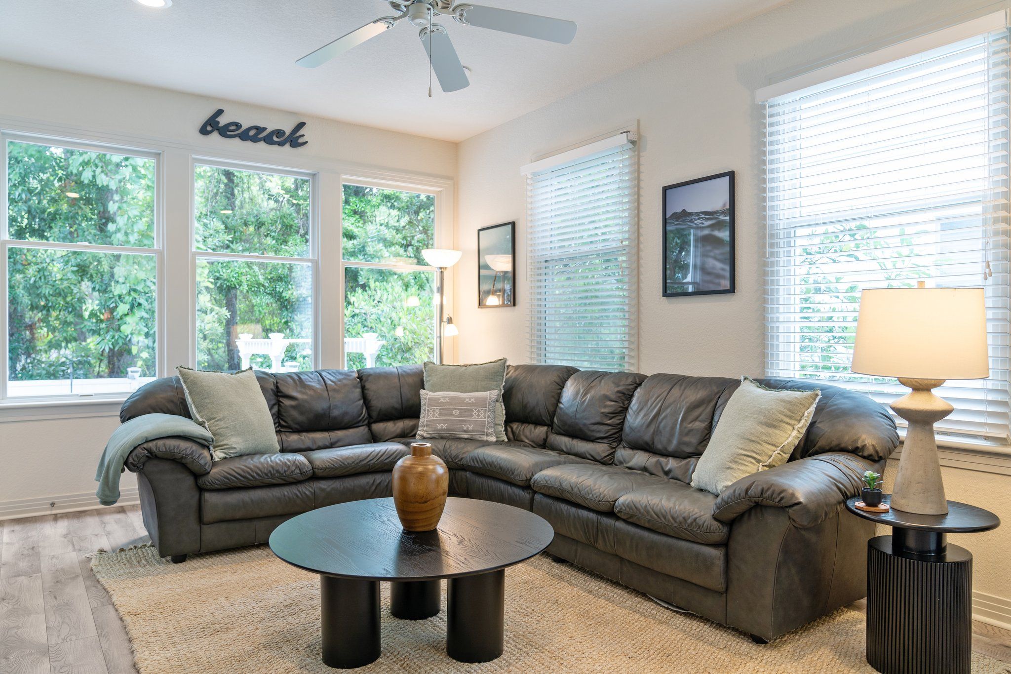 A living room with a sectional sofa, a coffee table, and a ceiling fan.
