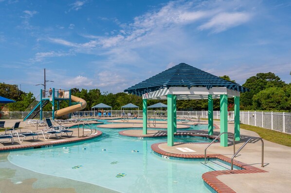 A swimming pool area with multiple pools, a slide, and a gazebo.