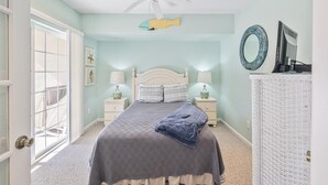 Een slaapkamer met een bed, twee nachtkastjes, een plafondventilator, een raam en een deur.