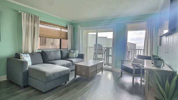 A living room with a grey sofa, a wooden coffee table, and a dining area with a table and chairs. - Beautiful Two Bedroom, Two Bath Condo at Sailport (Tampa)