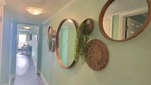 A hallway with a light green wall, decorative woven baskets, and mirrors. - Beautiful Two Bedroom, Two Bath Condo at Sailport (Tampa)