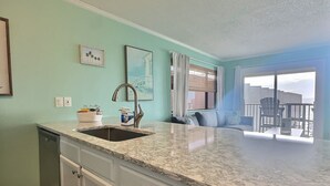 A kitchen with a sink, countertop, and cabinets. There is a dining area with a table and chairs. - Beautiful Two Bedroom, Two Bath Condo at Sailport (Tampa)