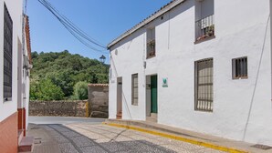 A narrow street with white buildings, a paved road, and a green door.