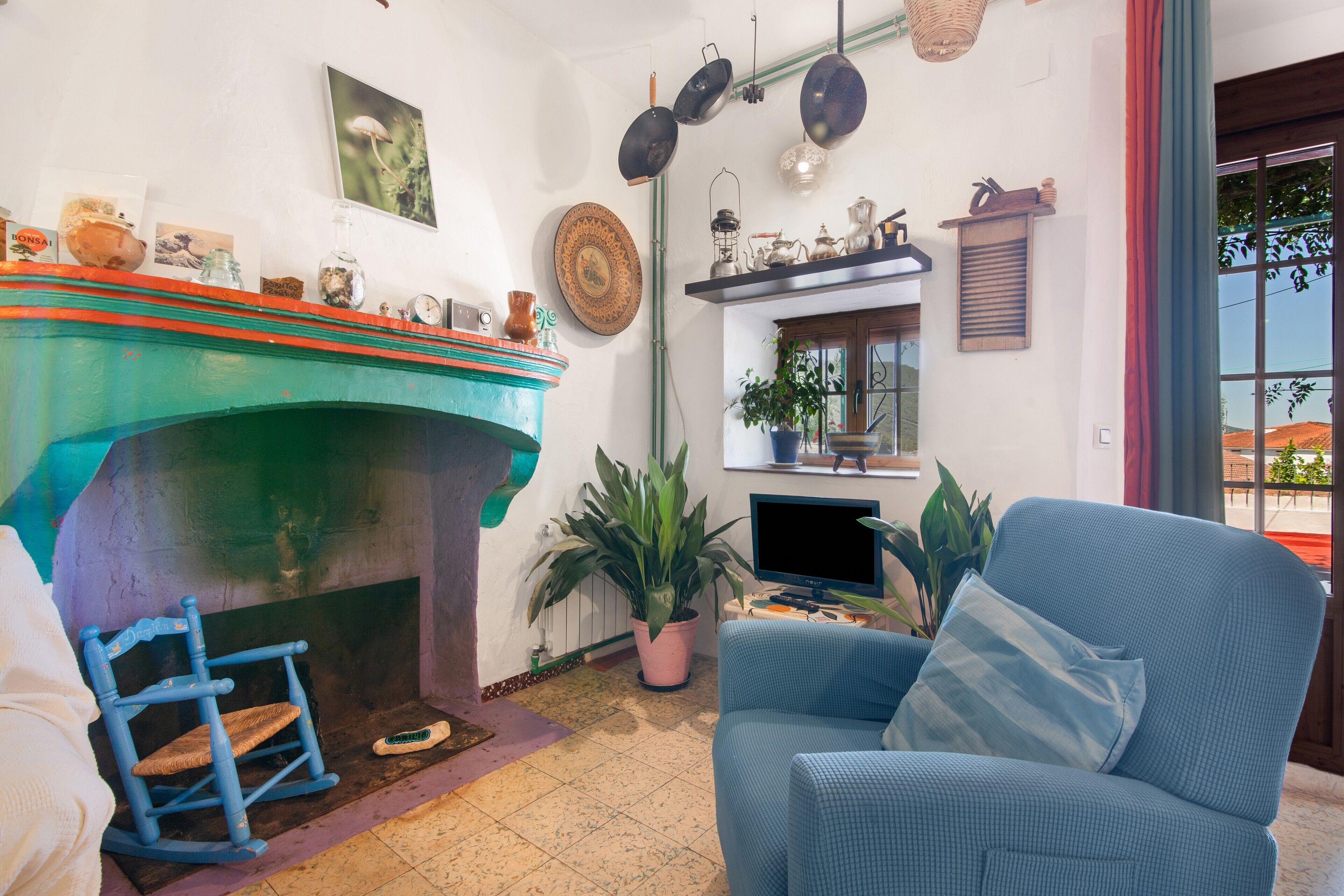 A cozy living room with a fireplace, a blue armchair, and a television.