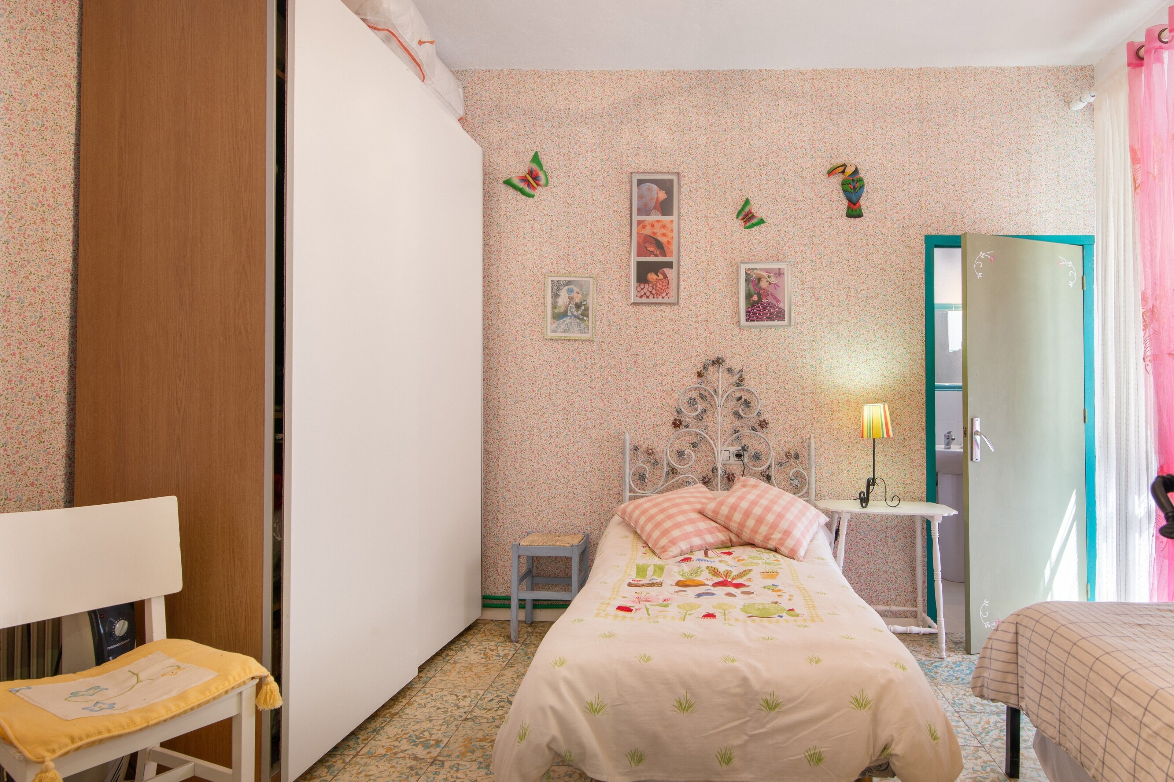 Un dormitorio con cama, una silla, una mesita y una puerta.