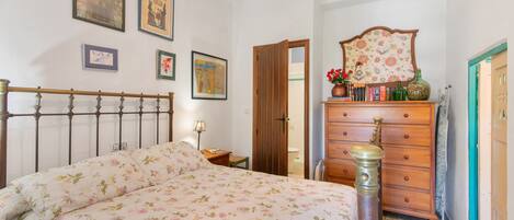 A bedroom with a bed, dresser, and wall-mounted artwork.