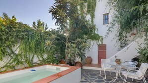 A stone-floored patio with a hot tub, white chairs, and lush greenery. - Country House 'La Rana Verde De Arriba' with Mountain Views, Private Terrace & Wi-Fi (Los Romeros)