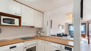 Een compacte keuken met een magnetron, oven, vaatwasser en wasmachine.